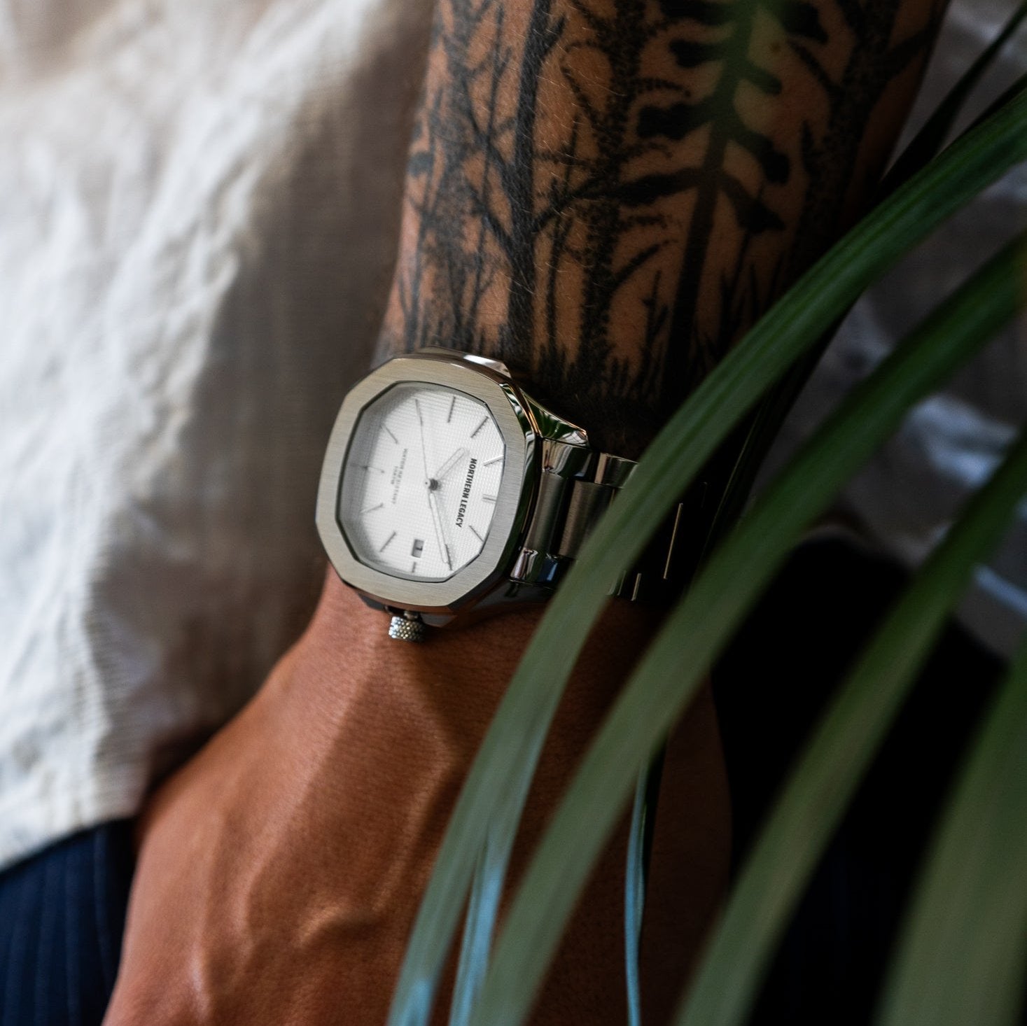 Herreur Fjord Hvid på tatoveret arm med grønne blade i forgrunden